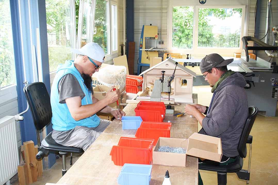 Bild von zwei Männern an Arbeitsplätzen im AKTIV Werk Wetterau im Bereich Montage.